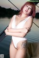 A woman in a white bathing suit posing on a boat.