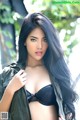 A woman with long black hair wearing a black bra and jacket.