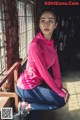 A woman in a pink shirt and blue leggings posing for a picture.