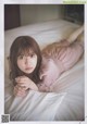 A woman laying on top of a bed next to a pillow.