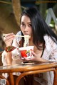 A woman sitting at a table eating a bowl of noodles.