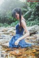 A woman in a blue dress is standing in the water.