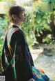 A woman in a colorful kimono sitting on a bench.