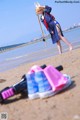 A woman in a bunny costume standing on a beach next to a pair of shoes.