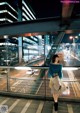 A woman standing on a bridge at night in a city.