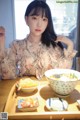 A woman sitting at a table with a bowl of food.