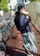 A woman walking down a sidewalk eating a piece of food.